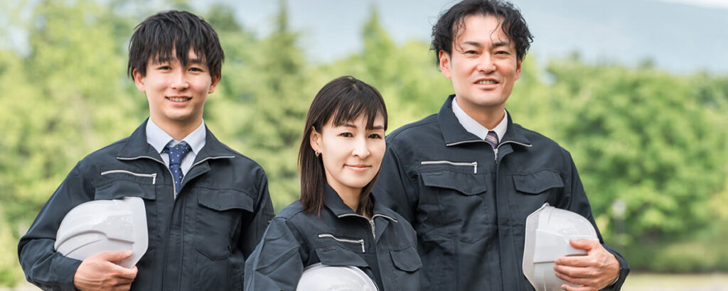 屋外で笑顔を見せる3人の施工スタッフ