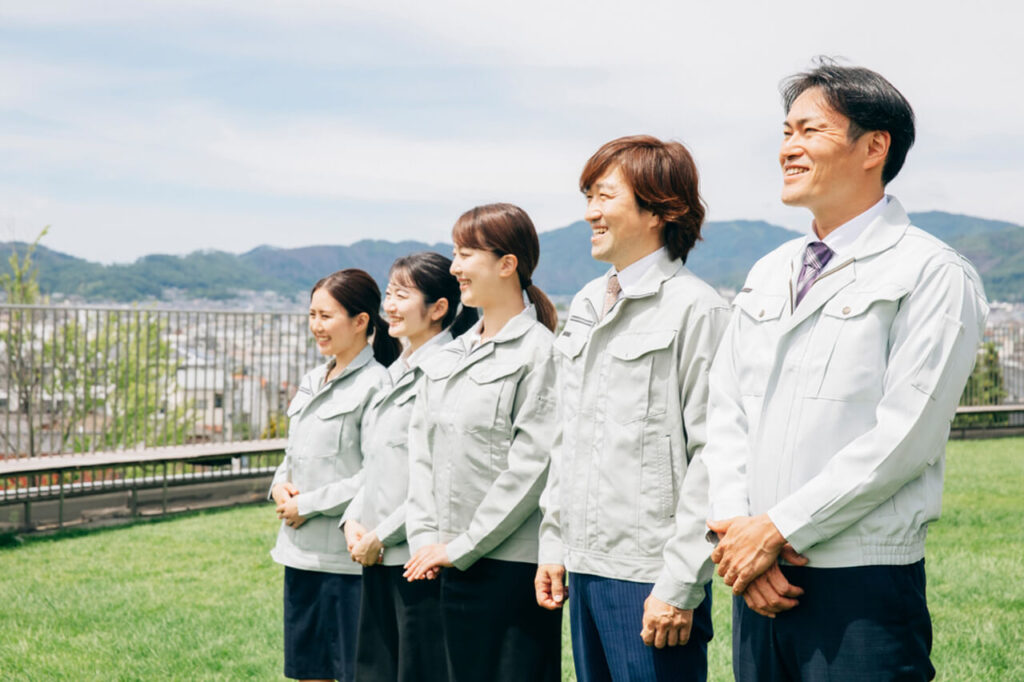 屋外で笑顔を見せる作業着姿のスタッフたち