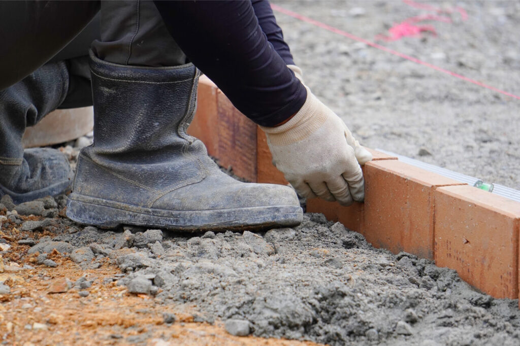 作業員が手作業でレンガを並べて施工している様子