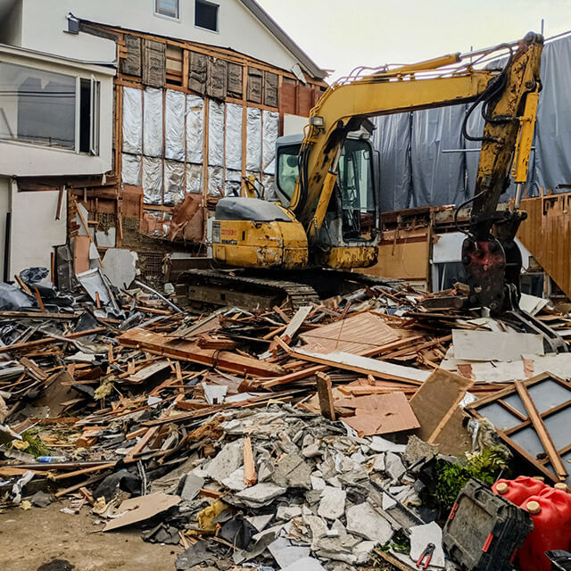 ショベルカーで家屋を取り壊す解体工事現場